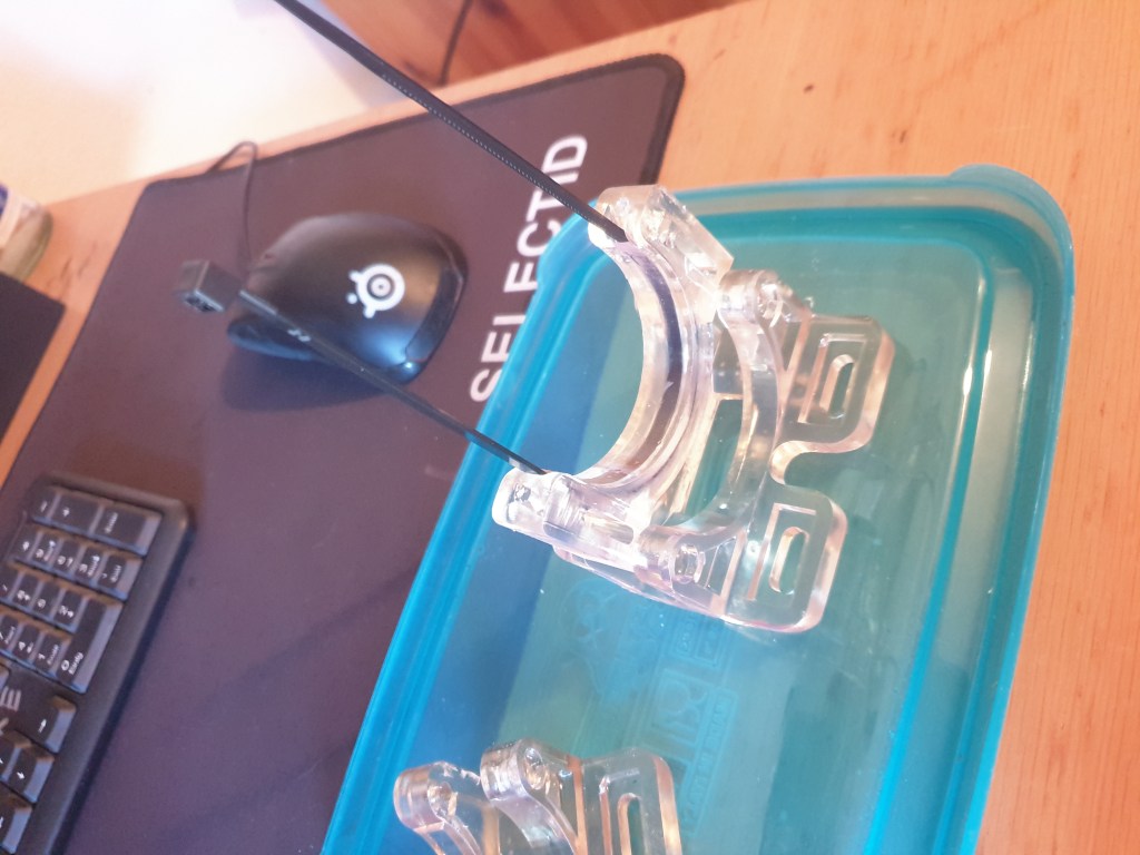 3D-printed resin holders with zip ties, placed on a table, ready for use in DIY CO2 laser setup for sealing implants.